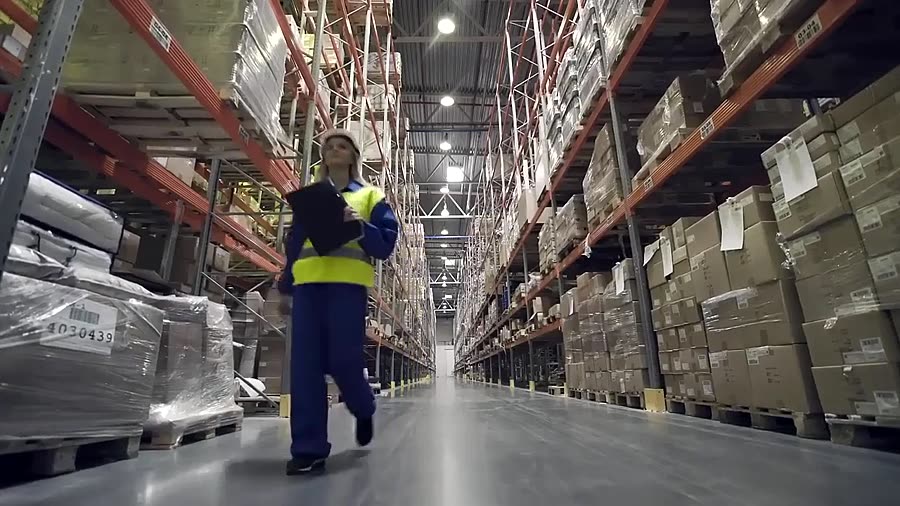 Supervisora con planilla recorriendo un centro de distribución